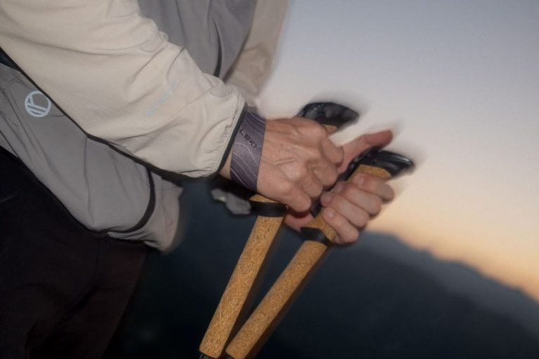 Händed, die Wanderstöcke halten, bei Dämmerung im Gebirge.